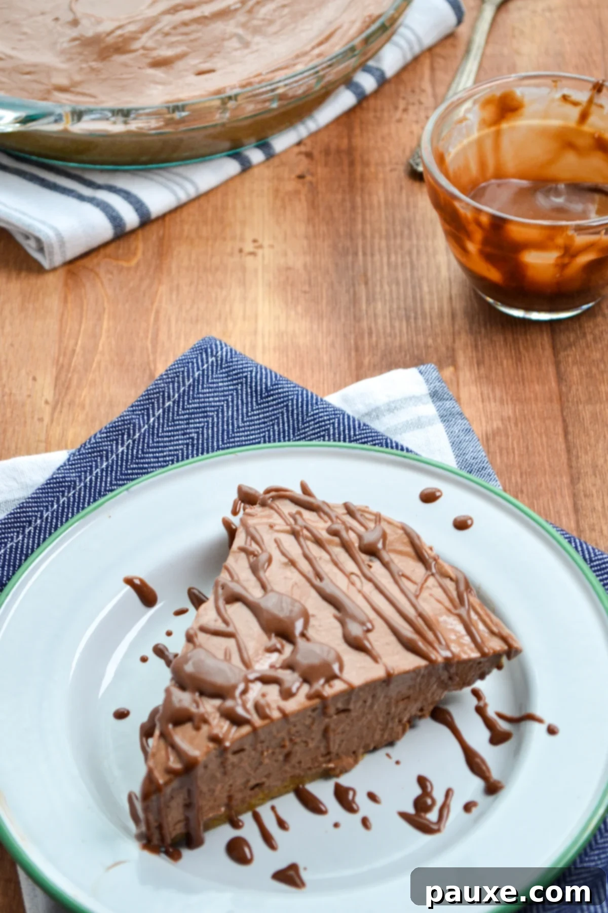 A slice of Nutella pie, beautifully drizzled with homemade Nutella ganache, ready to be enjoyed.