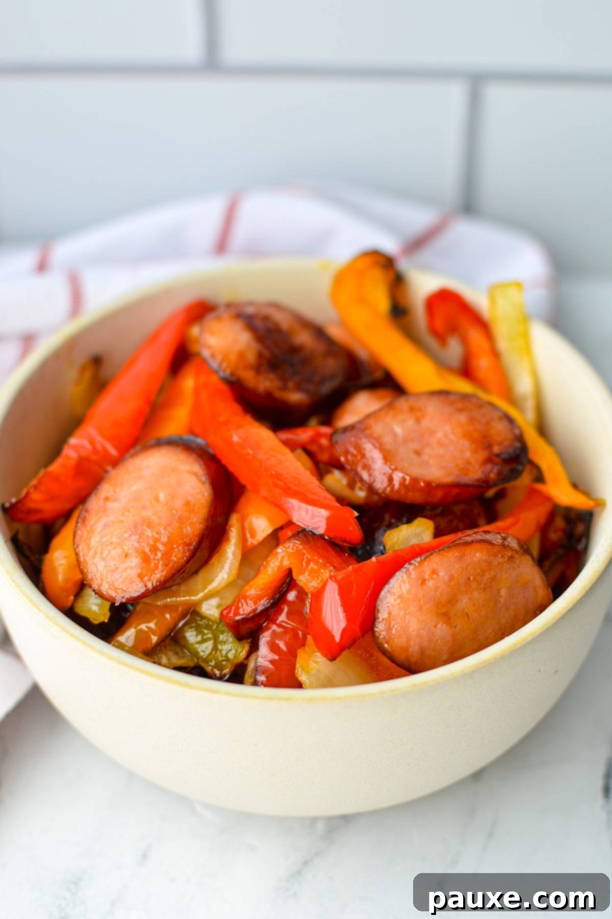 Crispy Air Fryer Sausage and Peppers 7 A bowl of sausage and peppers, with a white and red stripe napkin in the background.