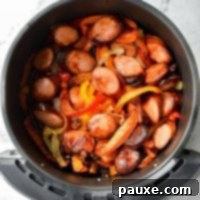Crispy Air Fryer Sausage and Peppers 8 An air fryer basket, filled with cooked sausage, peppers, and onions.