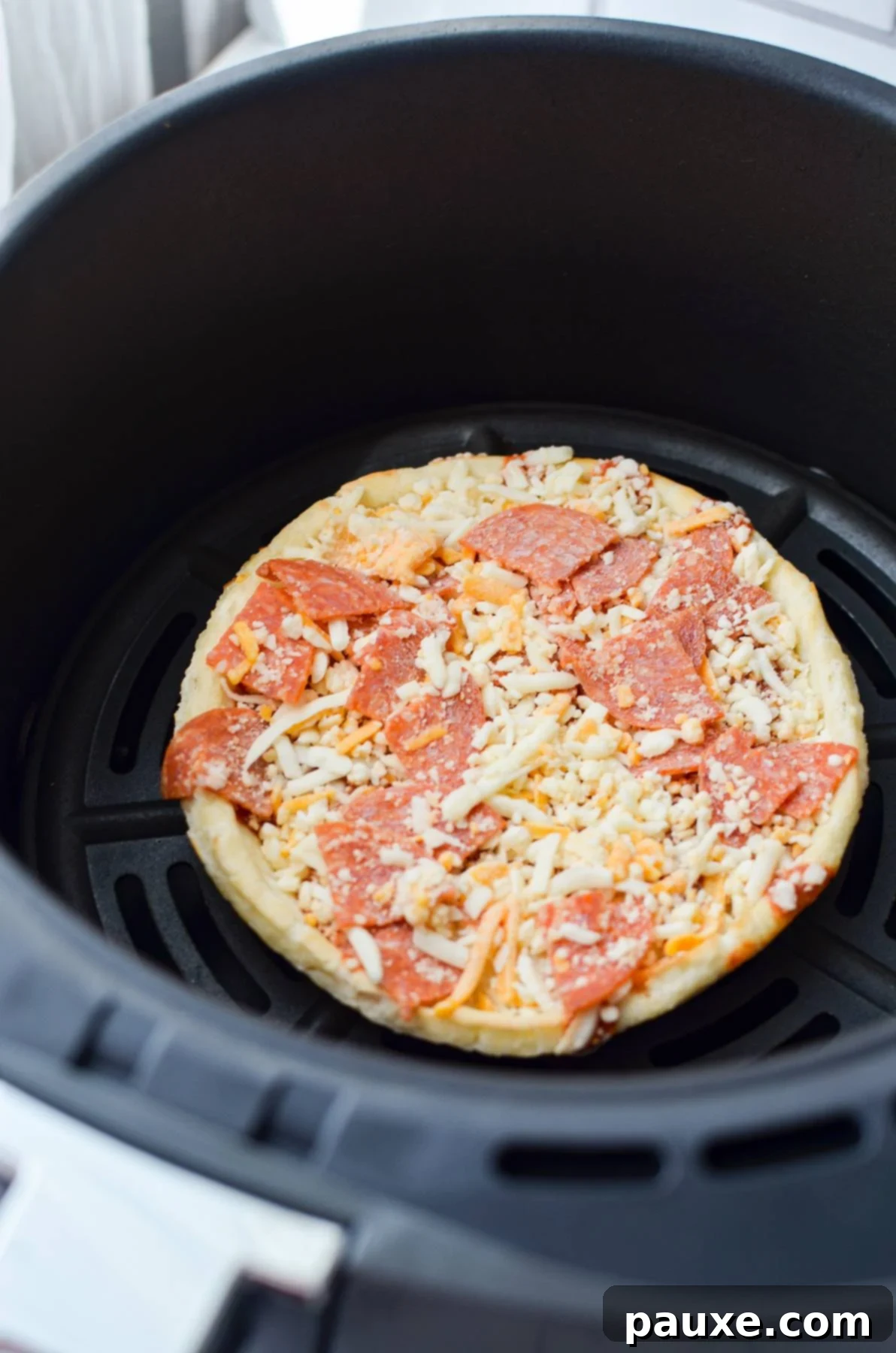 Crispy Air Fryer Frozen Mini Pizzas 4 A frozen mini pizza placed inside an air fryer basket, ready to be cooked.