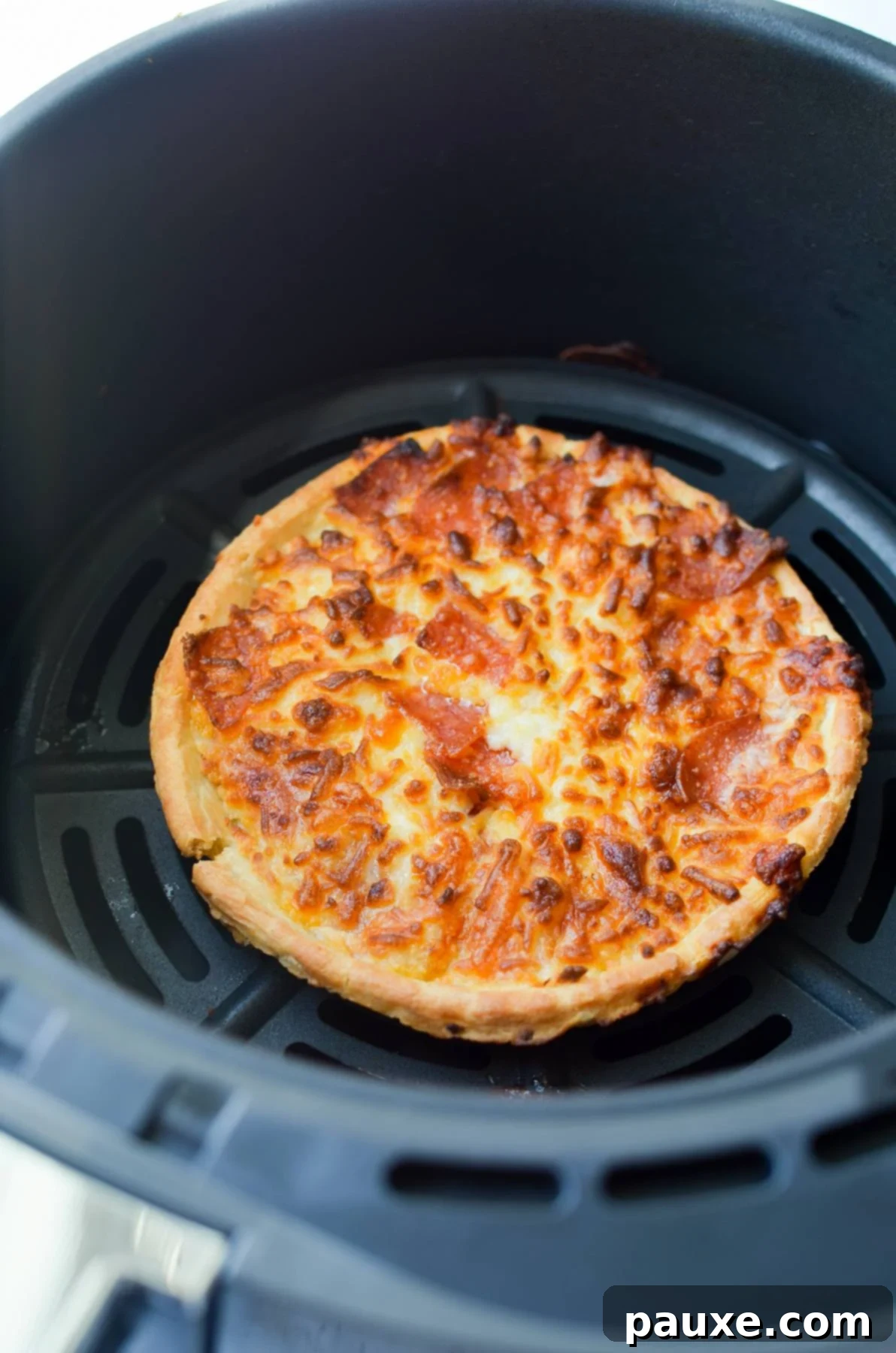 Crispy Air Fryer Frozen Mini Pizzas 5 A perfectly cooked mini pizza, hot and bubbly, inside an air fryer basket.