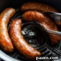 Crispy Air Fryer Italian Sausages 6 An air fryer basket with Italian sausages, being lifted out with tongs.