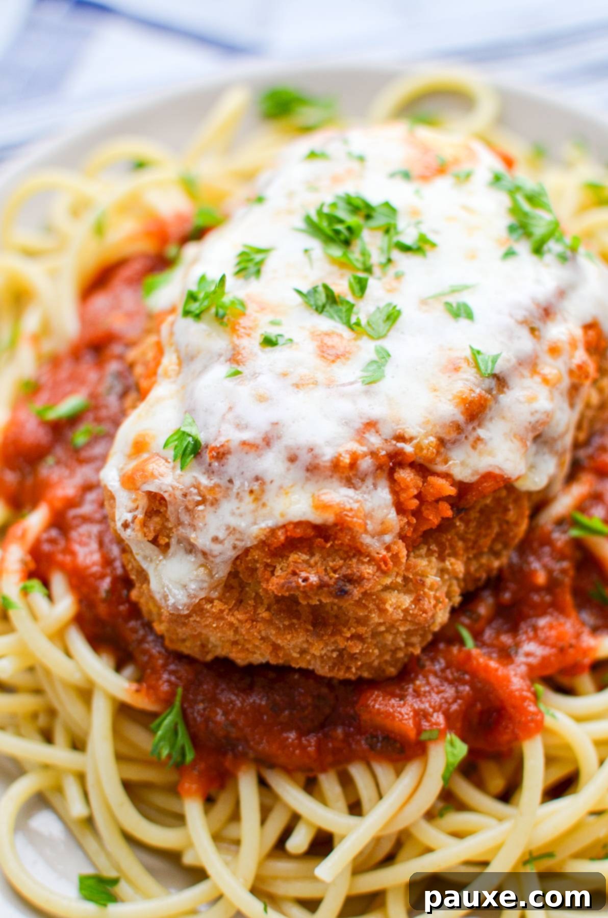 A crispy, golden-brown cutlet of air-fried frozen chicken parmesan resting on a fluffy bed of cooked spaghetti, highlighting its inviting texture.