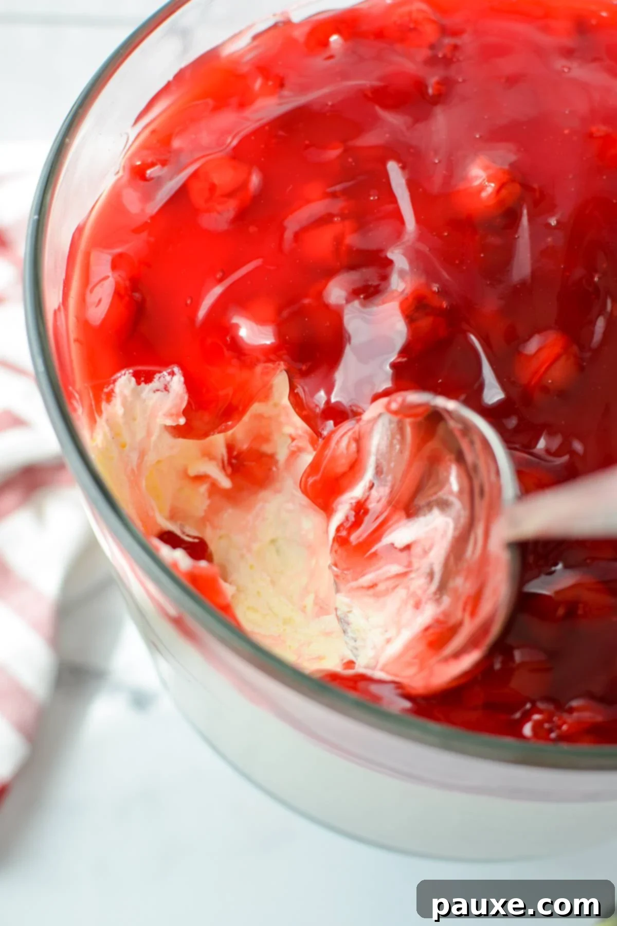 Effortless Cheesecake Delight 12 A spoon scooping out a generous portion of lazy cheesecake salad, revealing the creamy layers beneath the fruit topping, inviting a taste.