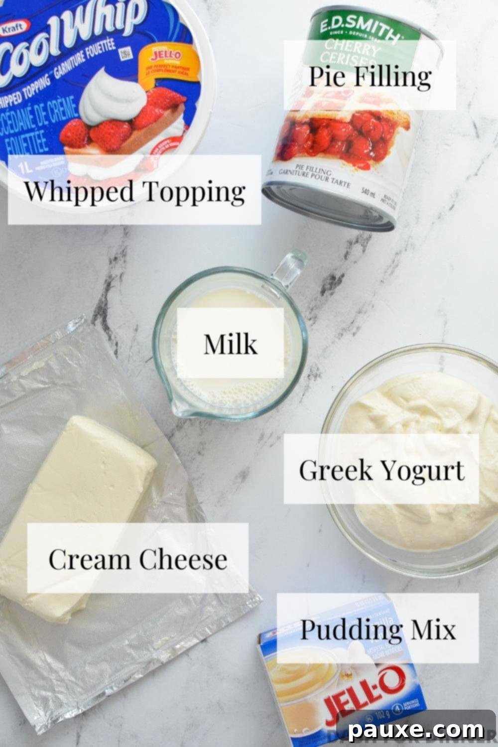 Effortless Cheesecake Delight 3 All the essential ingredients neatly arranged for making a no-bake cheesecake salad, including cream cheese, whipped topping, milk, pudding mix, Greek yogurt, and cherry pie filling.