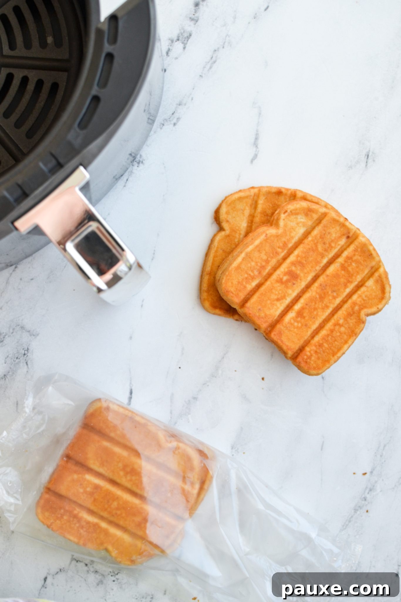 A close-up view of frozen French toast sticks, with an air fryer basket subtly blurred in the background, highlighting the key components for this quick recipe.