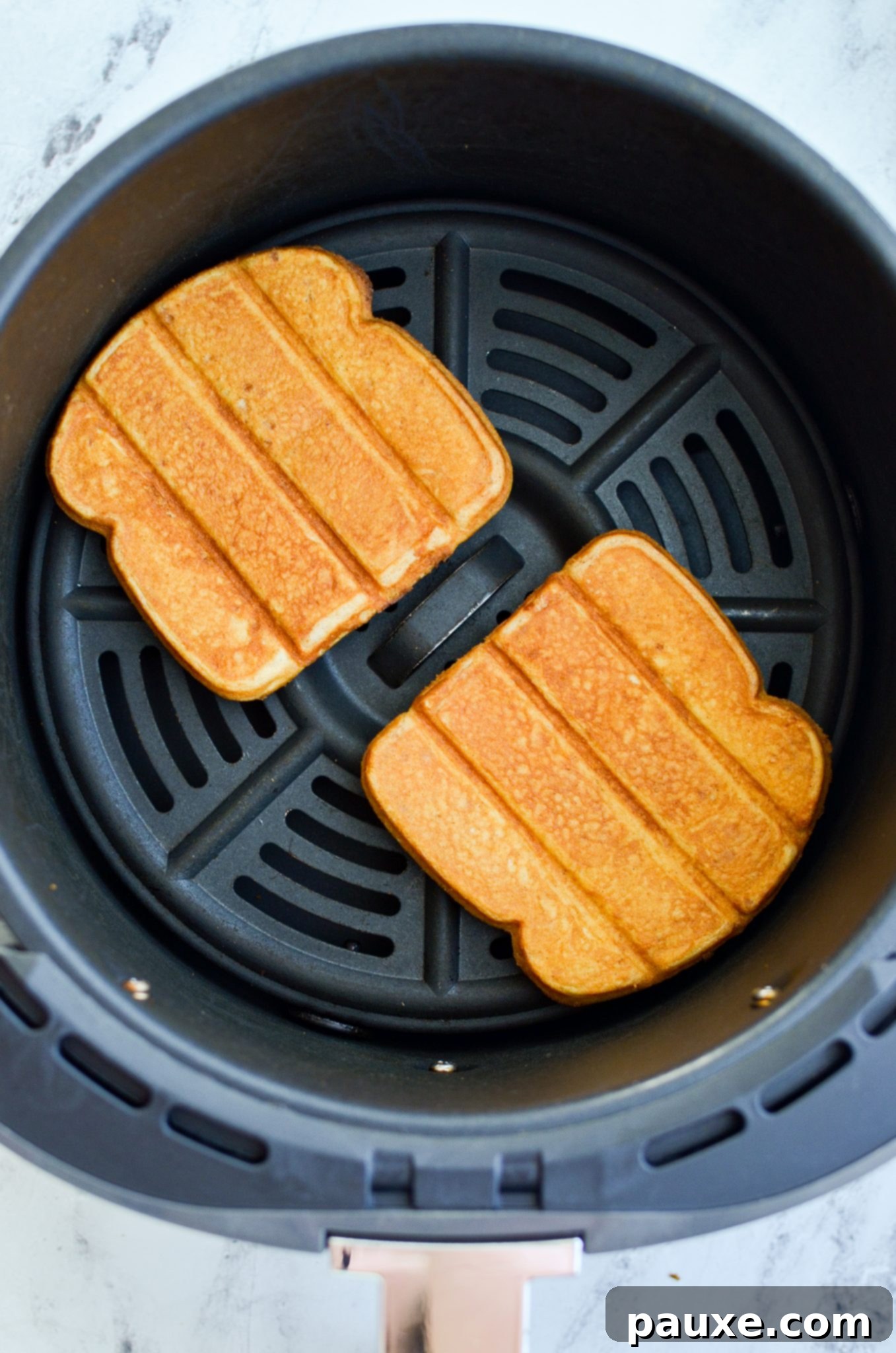 Frozen French toast sticks being carefully placed in a single layer into an air fryer basket for optimal cooking.