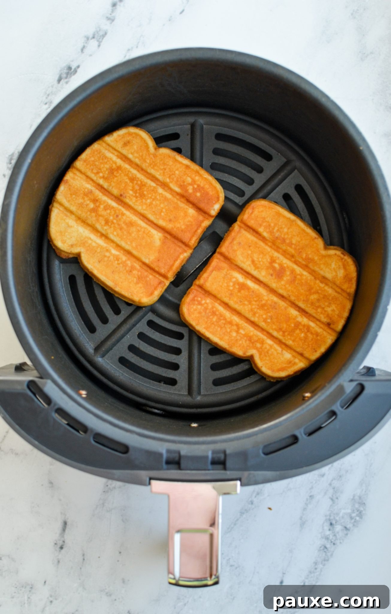 Perfectly browned and crispy French toast sticks resting in an air fryer basket, ready to be served after cooking.
