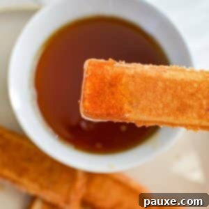 Dipping a French toast stick into a bowl of maple syrup.