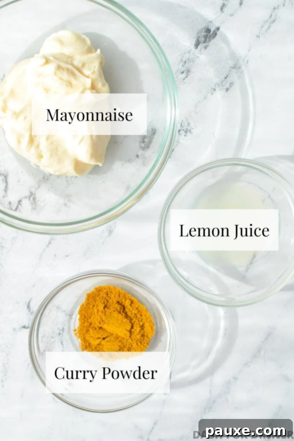 Creamy Homemade Curry Aioli 3 A small bowl of mayonnaise, another one of fresh lemon juice, and a third with vibrant curry powder, laid out on a clean surface.