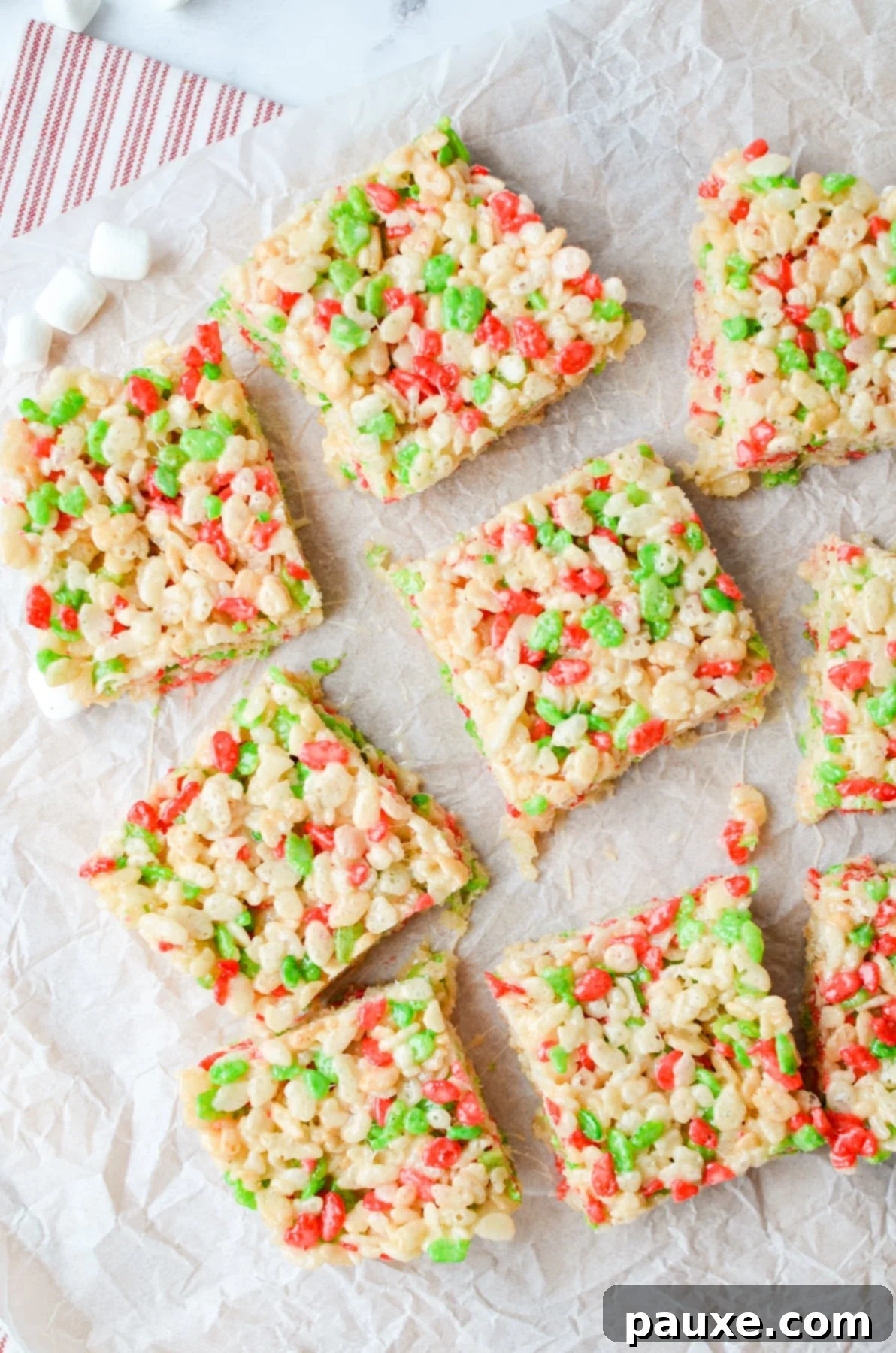 Festive Christmas Rice Krispie Treats 6 9 holiday Rice Krispies Treats cut on a piece of parchment.