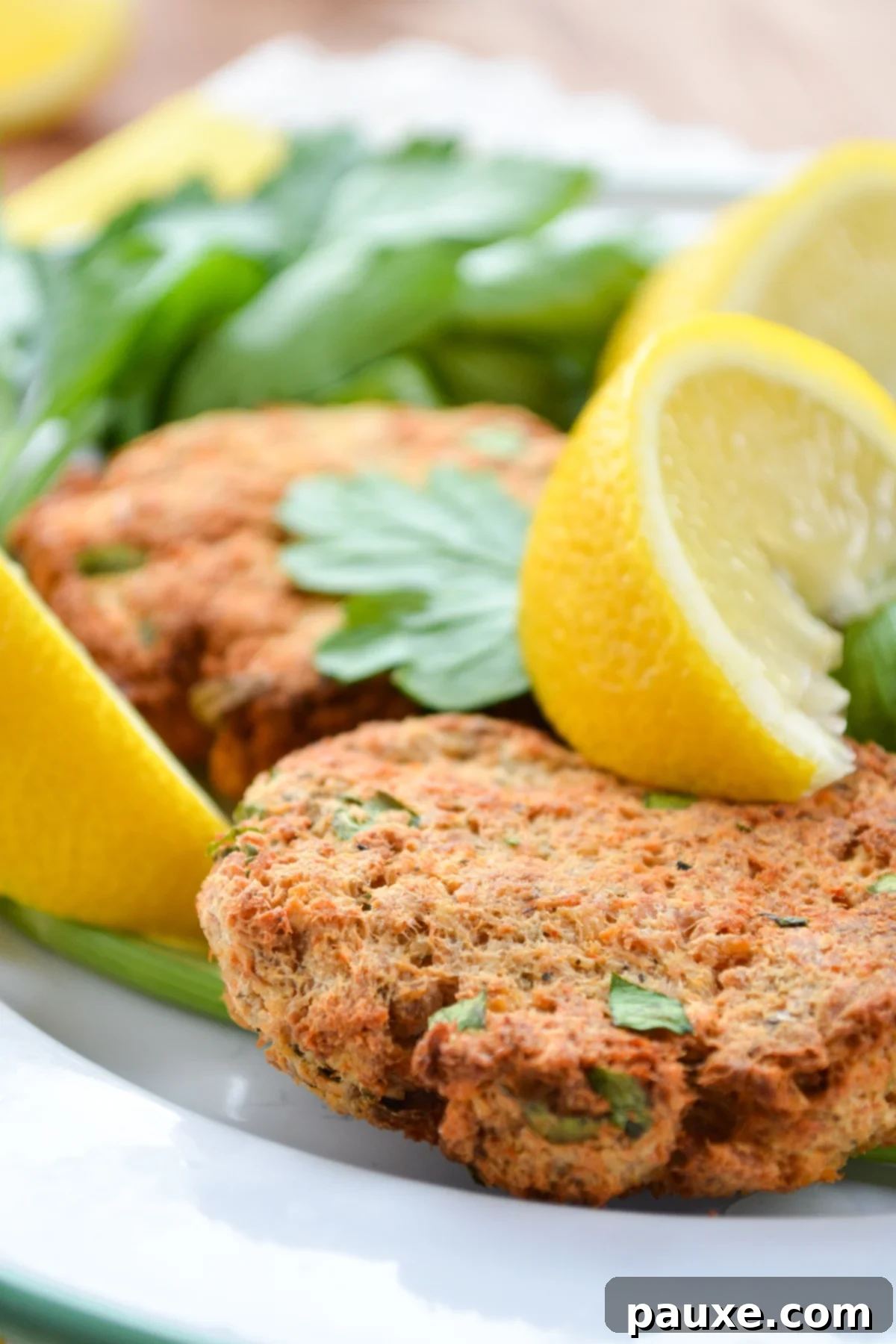 Crispy Air Fryer Salmon Cakes 2 A plate of salmon patties, garnished with parsley and lemon wedges.