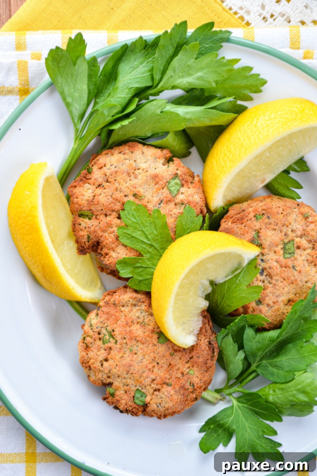 Crispy Air Fryer Salmon Cakes 11 Salmon patties served on a plate, garnished with parsley and lemon.