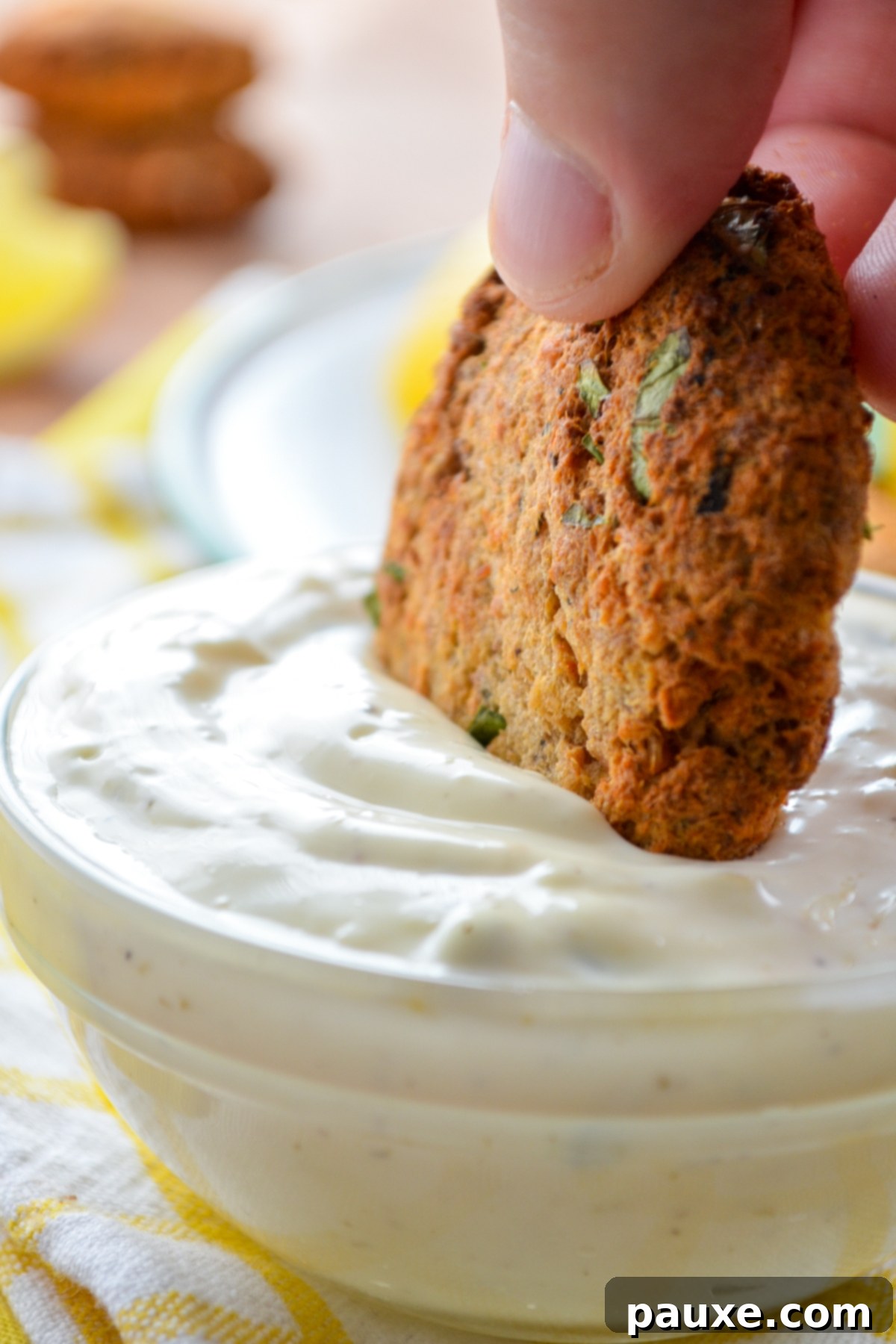 Crispy Air Fryer Salmon Cakes 10 A salmon cake being dipped into a homemade tartar sauce.