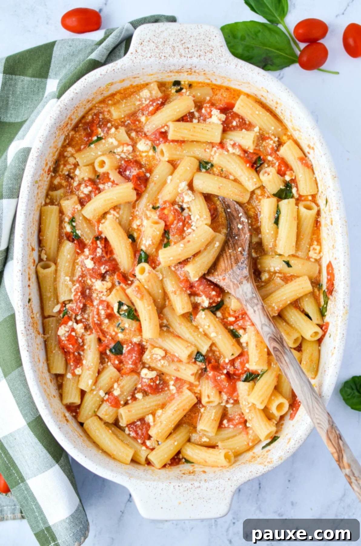 Roasted Tomato and Feta Pasta 2 A baking dish with a tomato and pasta dish garnished with fresh basil, ready to be served.