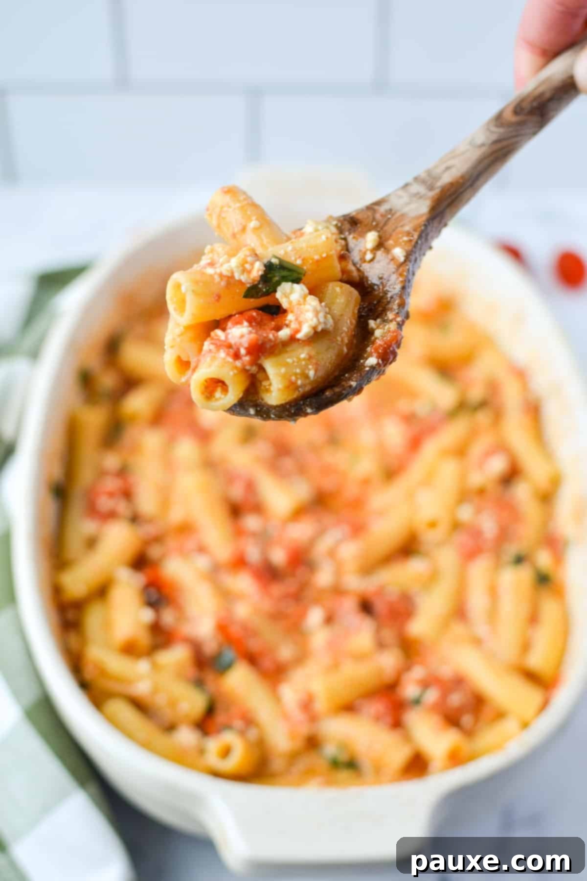 Roasted Tomato and Feta Pasta 6 A baking dish filled with baked feta pasta, with a serving spoon taking a portion.