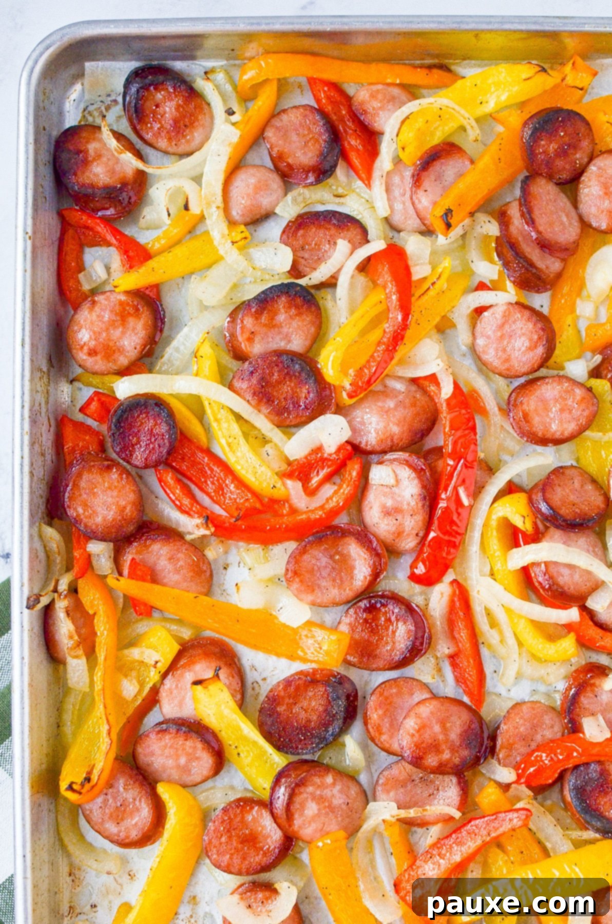 One-Pan Smoked Sausage and Peppers Feast 2 A sheet pan filled with perfectly roasted sliced sausages, colorful bell peppers, and tender onions, ready to serve.