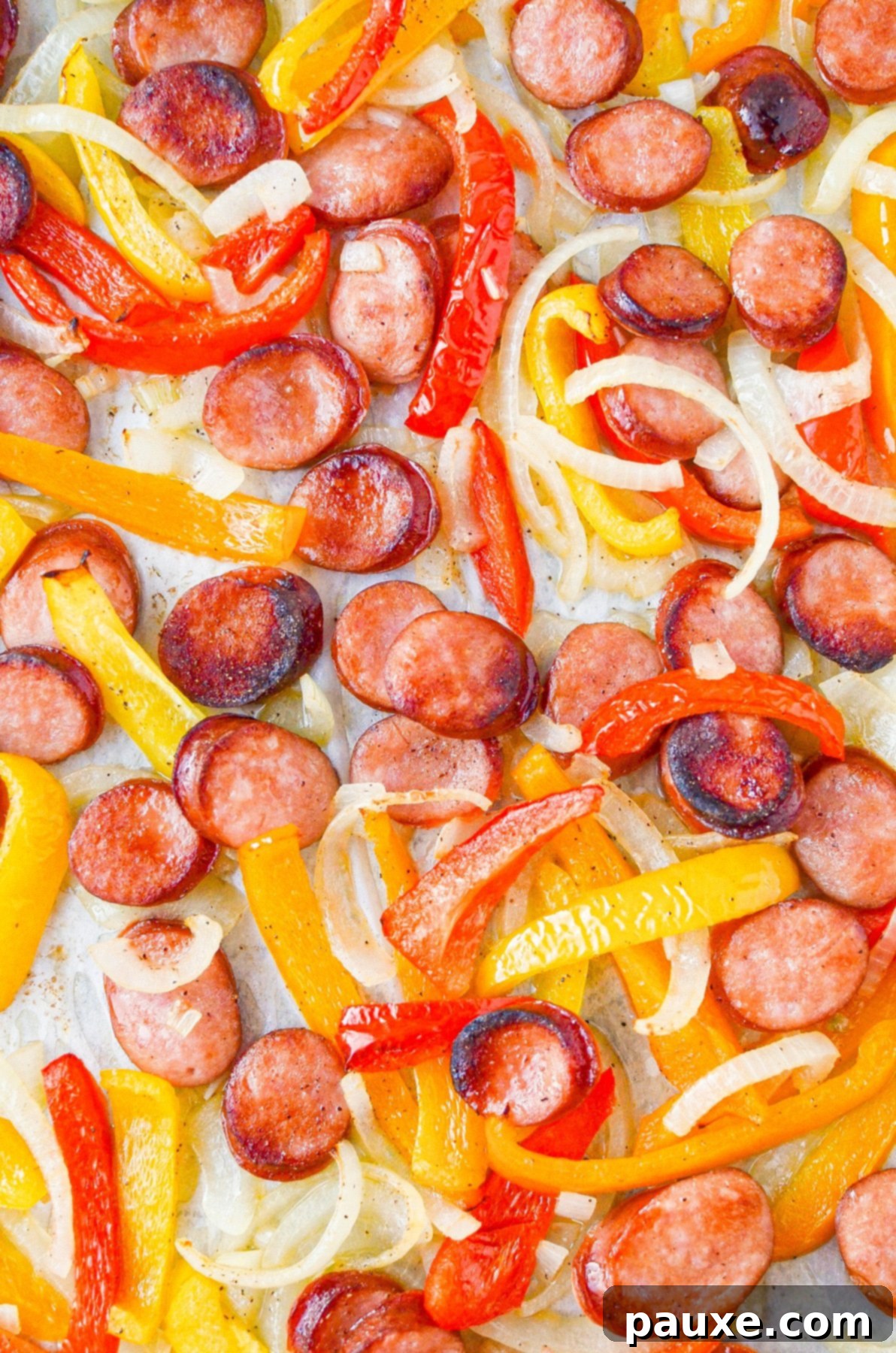 One-Pan Smoked Sausage and Peppers Feast 6 Perfectly roasted sausage rounds, vibrant bell peppers, and tender onions spread evenly on a sheet pan, fresh out of the oven.