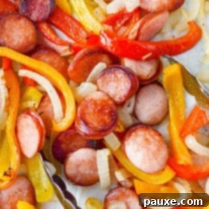 One-Pan Smoked Sausage and Peppers Feast 9 Tongs taking a portion of sausage rounds with peppers and onions.