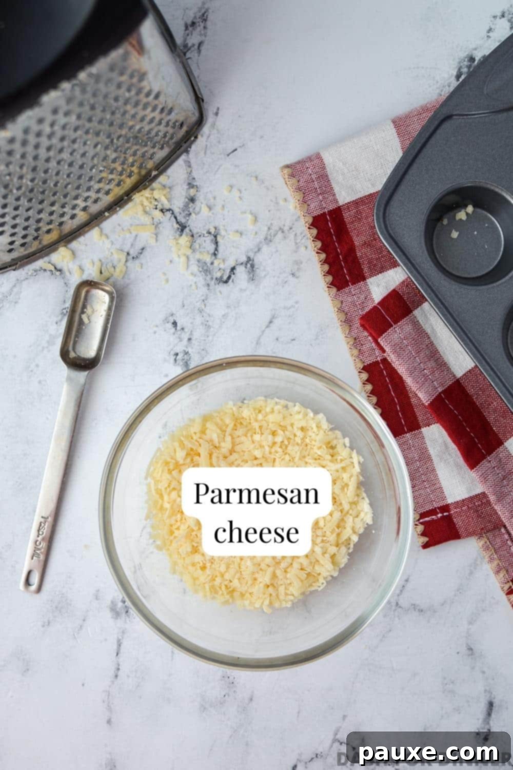 Crispy Parmesan Bites 3 A bowl of finely shredded Parmesan cheese next to a box grater and a mini muffin tin, highlighting the simple tools needed for the recipe.