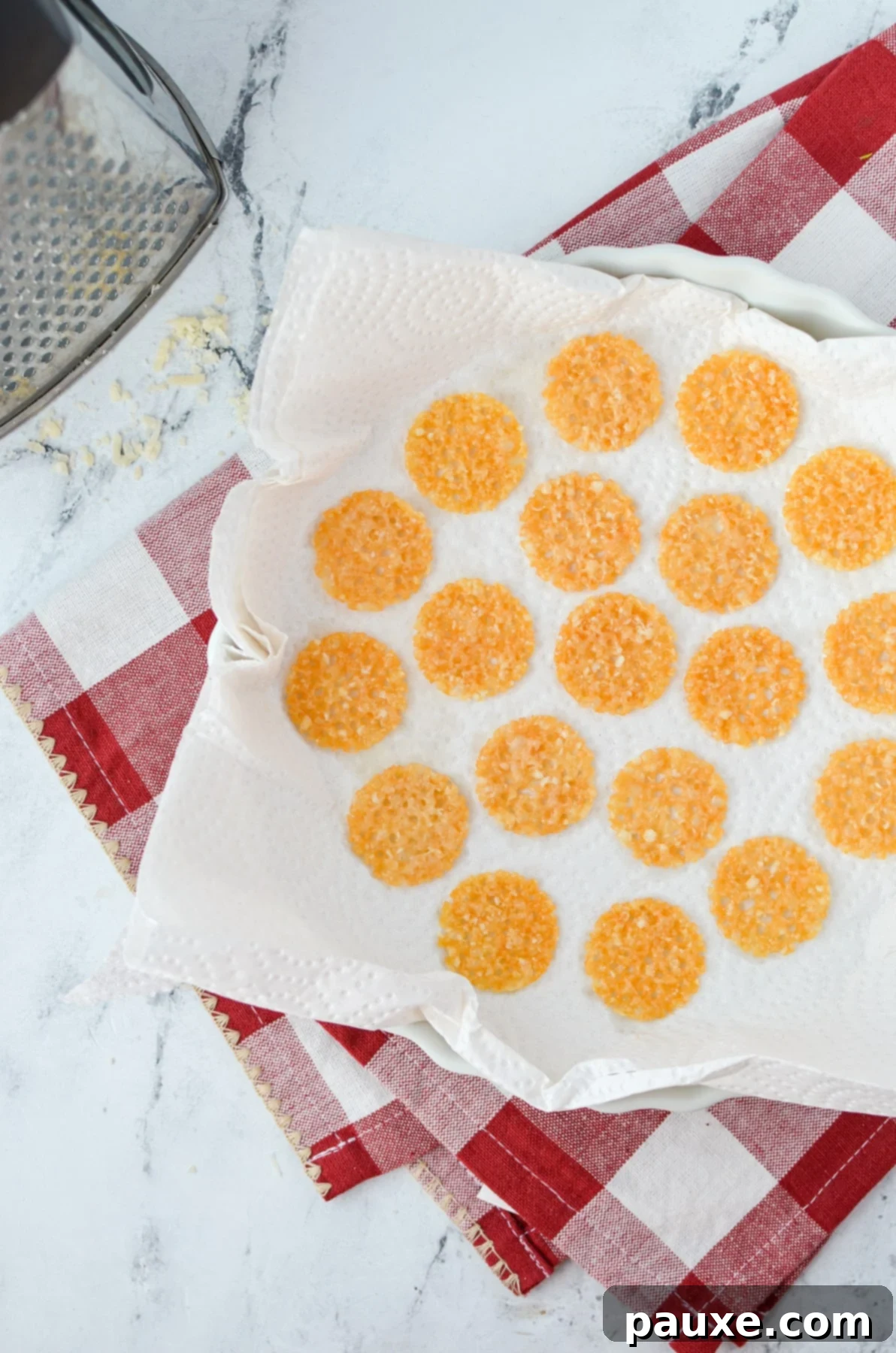 Crispy Parmesan Bites 5 Freshly baked, golden Parmesan crisps being carefully transferred with a fork onto a plate lined with paper towels to drain excess oil.