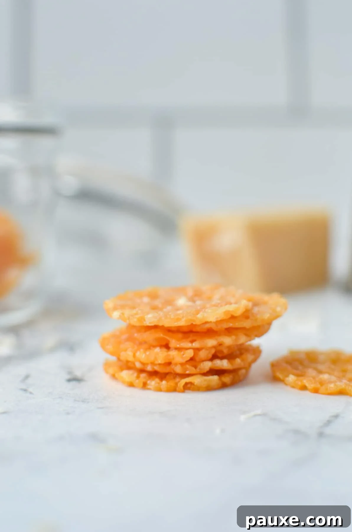 Crispy Parmesan Bites 8 A neatly stacked pile of golden Parmesan Crisps on a marble countertop, showcasing their uniform shape and crispy texture.