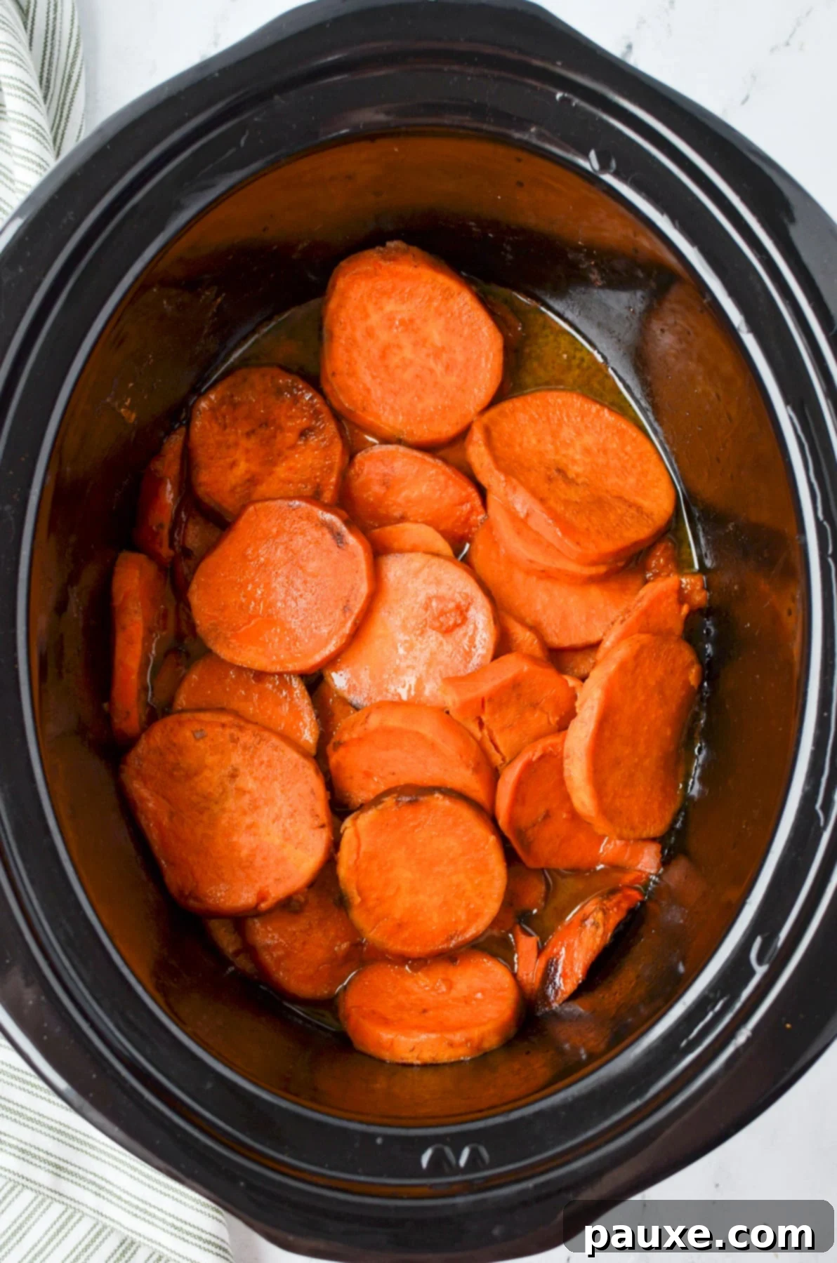 Slow Cooker Candied Sweet Potatoes 6 A slow cooker filled with beautifully cooked, tender glazed sweet potato slices, glistening in their sweet sauce, ready to be thickened and served as a delicious side.