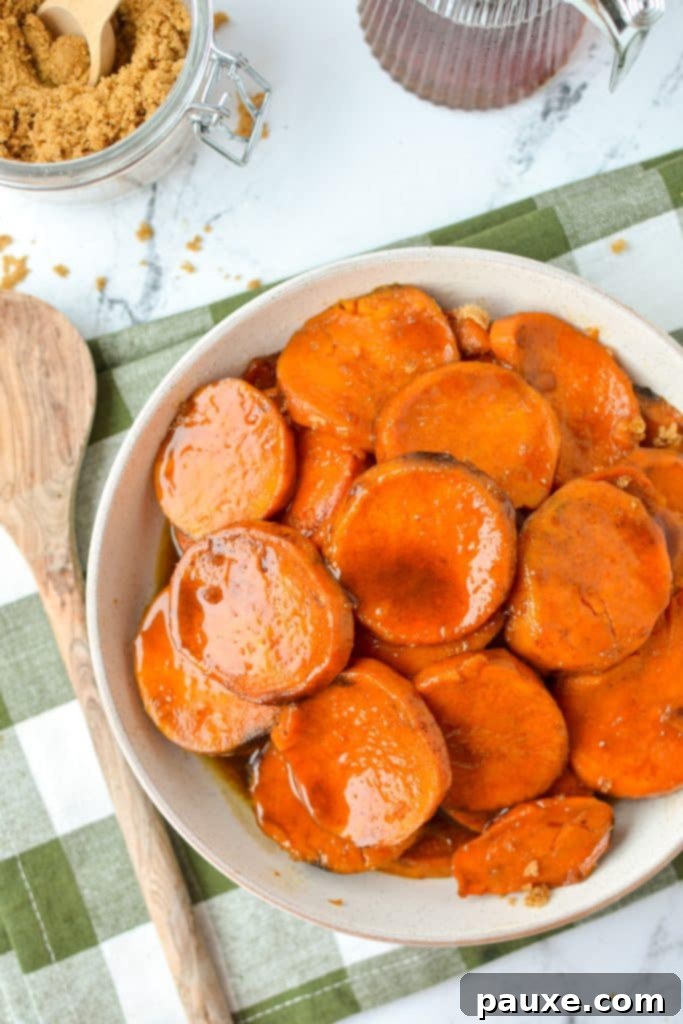 Slow Cooker Candied Sweet Potatoes 9 A close-up view of a shallow bowl filled with beautifully cooked sweet potato slices, each one coated in a glistening, sweet, and spiced glaze, highlighting their tender texture and festive appeal.