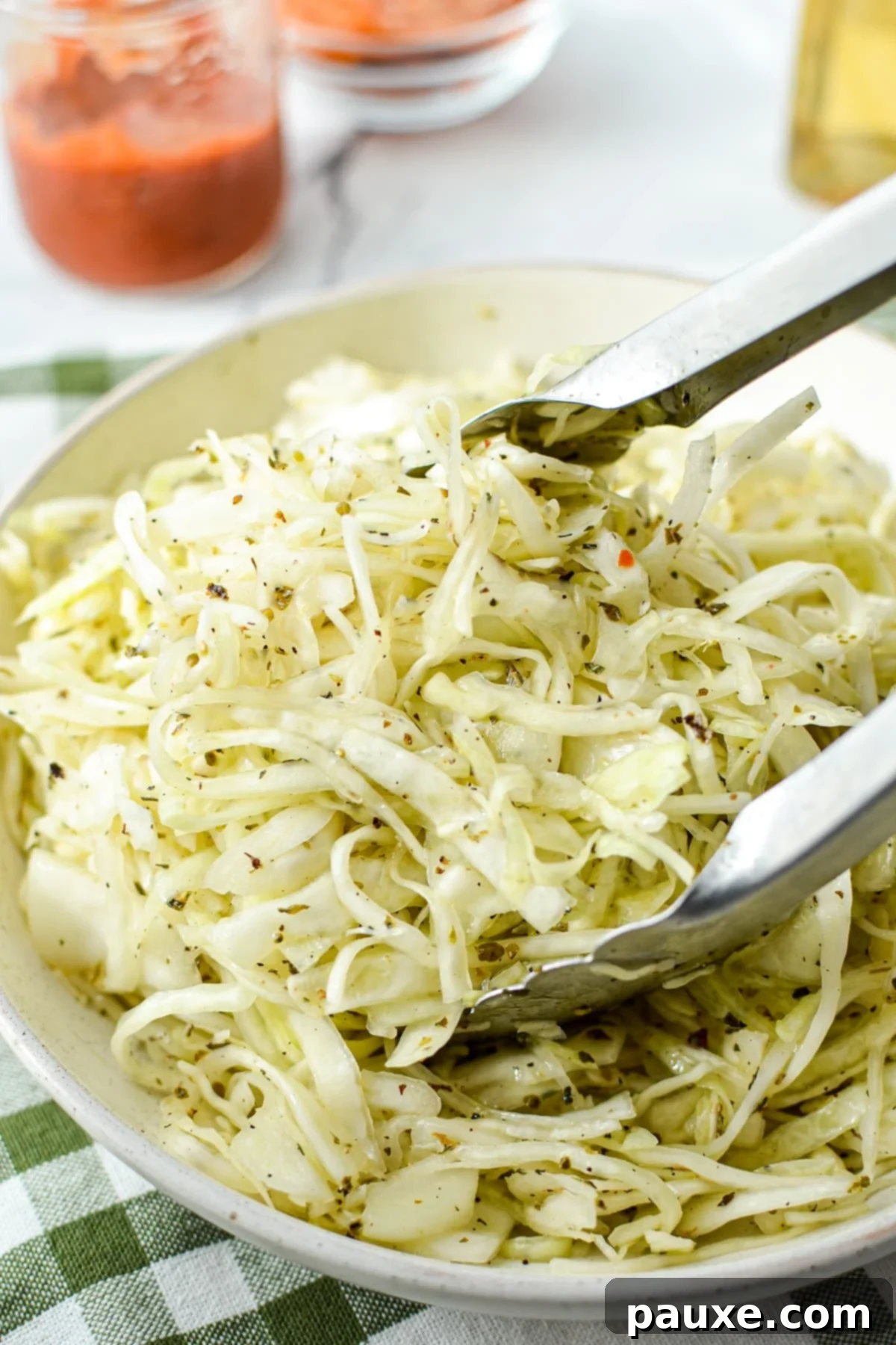Swedish Pizza Slaw 2 Tongs gently tossing a vibrant, oil and vinegar coleslaw in a large bowl, highlighting its fresh texture and appealing dressing.