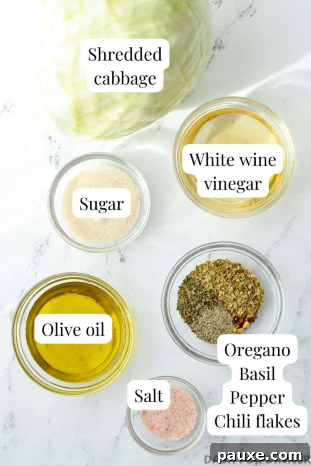 Swedish Pizza Slaw 3 A flat lay photograph showcasing the essential ingredients for Swedish Pizza Salad: a bottle of vinegar, a bottle of olive oil, a small bowl of dried herbs (oregano and basil), a pile of coarse salt, and a small dish of sugar.