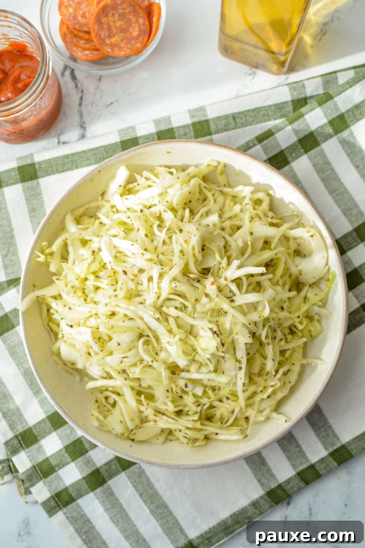 Swedish Pizza Slaw 7 A large bowl of vibrant shredded cabbage topped with a glistening oil and vinegar dressing, ready for marinating or serving.