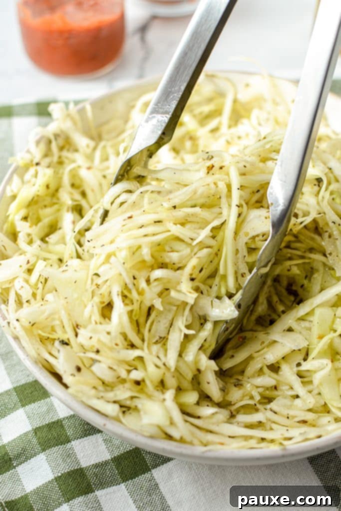 Swedish Pizza Slaw 8 Close-up of tongs tossing a refreshing cabbage salad, highlighting its crisp texture and the vibrant green of the cabbage leaves.
