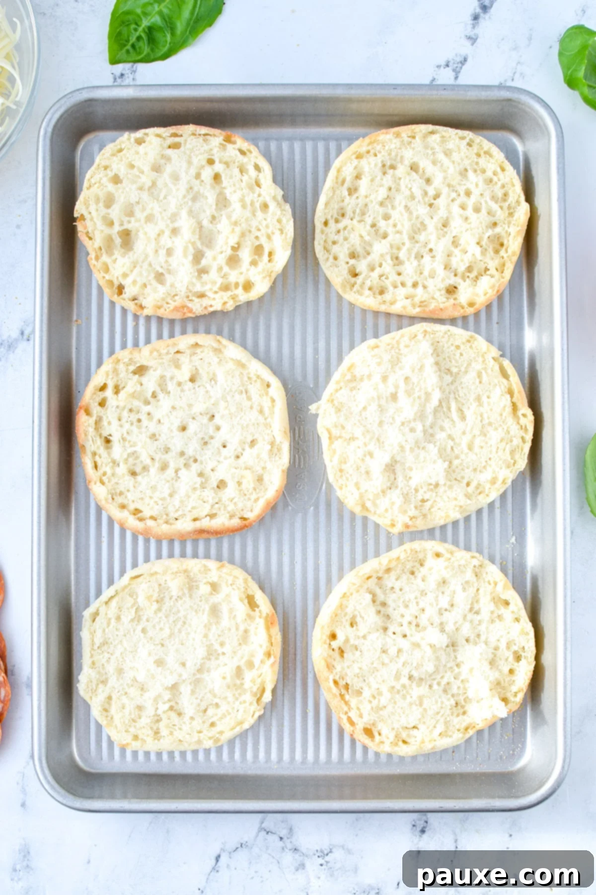 A baking sheet with English muffin halves on it.