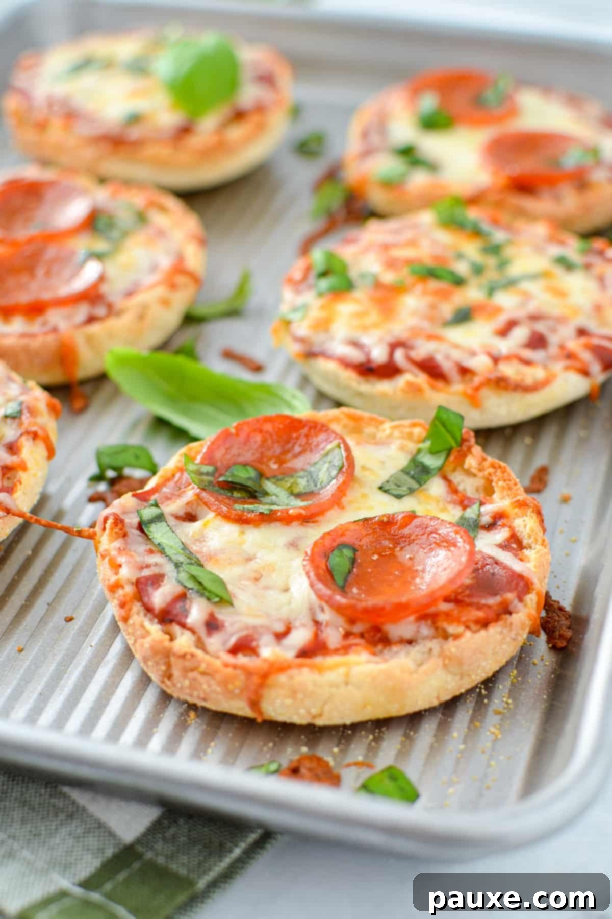 A baking sheet with baked mini pizzas on them.
