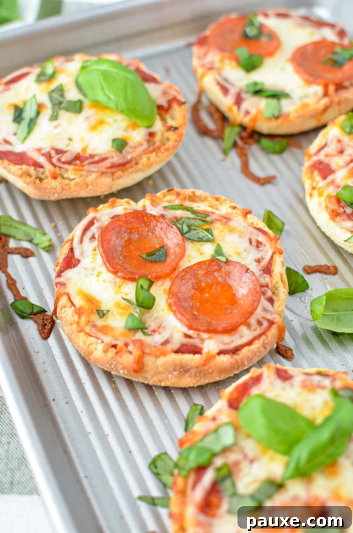 A close up of a mini pizza topped with pepperoni and basil.