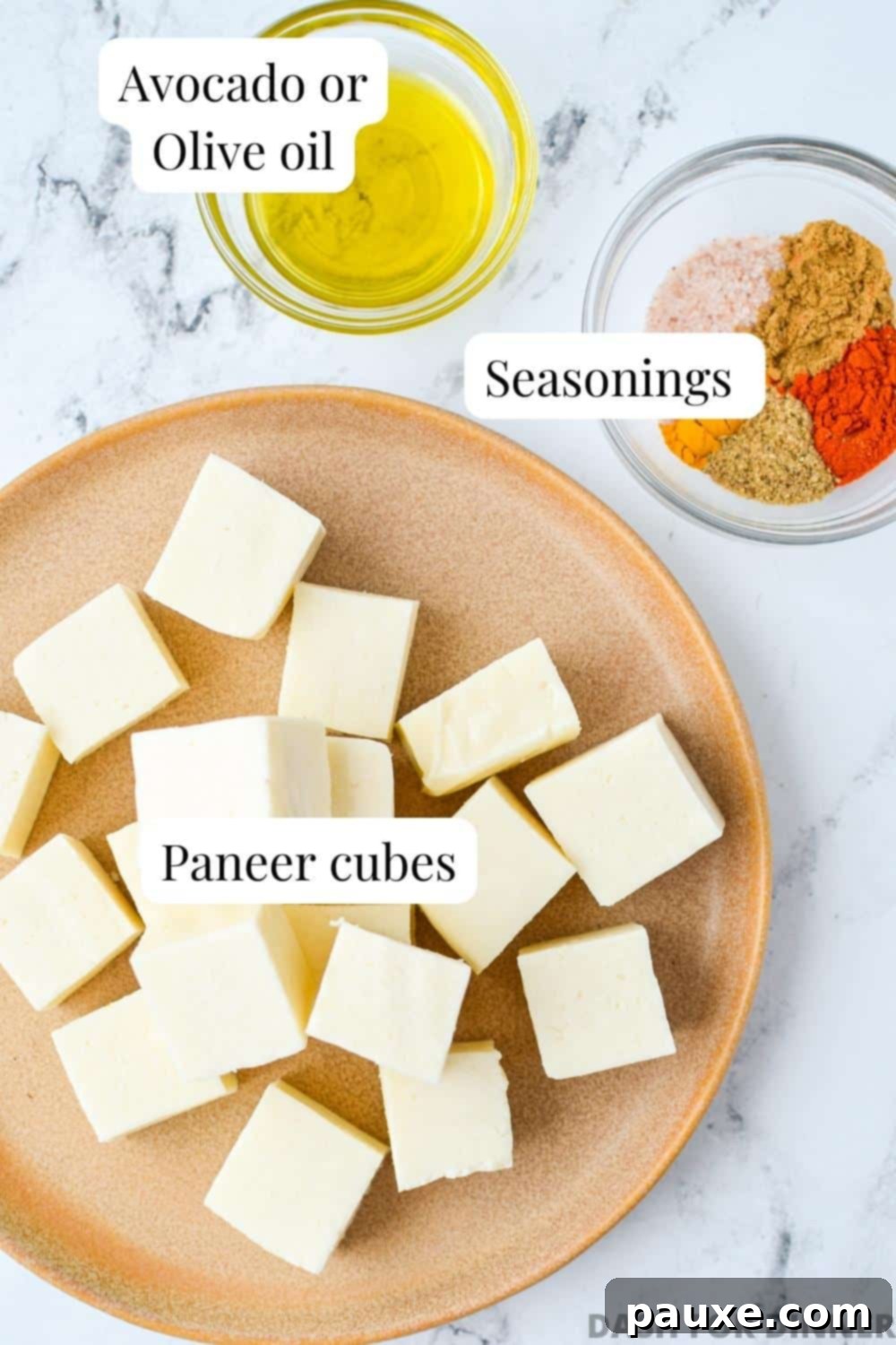 The simple ingredients needed to make air fryer paneer: a block of paneer, a bottle of oil, and small bowls of various seasonings.