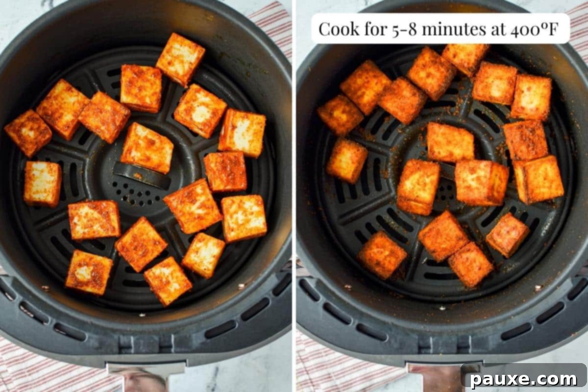 An air fryer basket filled with beautifully seasoned and cooked paneer cubes, golden and crispy.