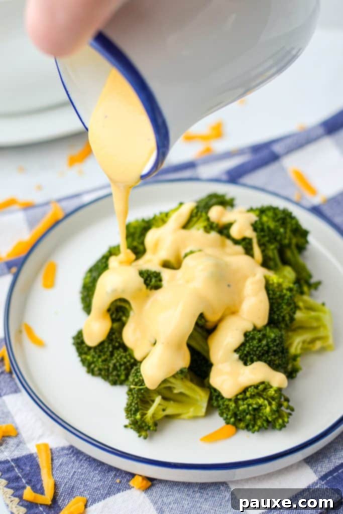 Mom's Legendary Cheese Sauce 11 Drizzling rich, golden homemade cheese sauce liberally on top of a serving of fresh, steamed broccoli, making it an irresistible dish.