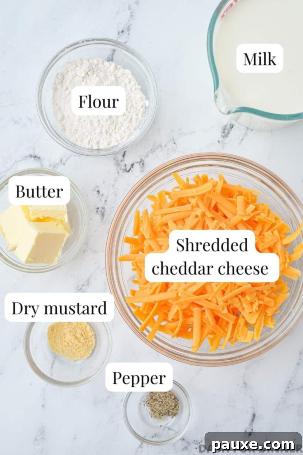 Mom's Legendary Cheese Sauce 4 The ingredients needed to make cheese sauce: freshly shredded sharp cheddar cheese, butter, whole milk, all-purpose flour, dry mustard powder, salt, and black pepper.