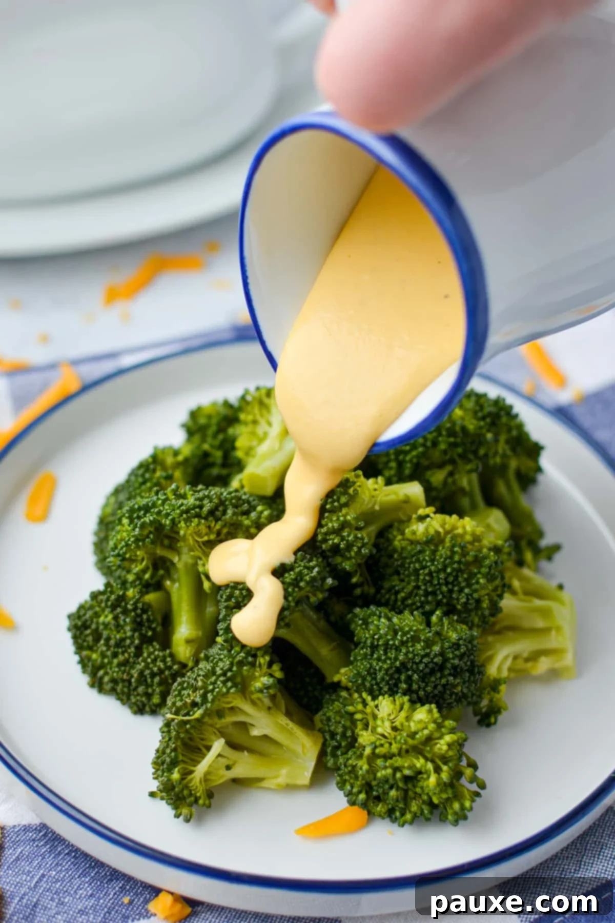 Mom's Legendary Cheese Sauce 9 Delicious cheese sauce being drizzled liberally on top of a serving of fresh, vibrant broccoli.
