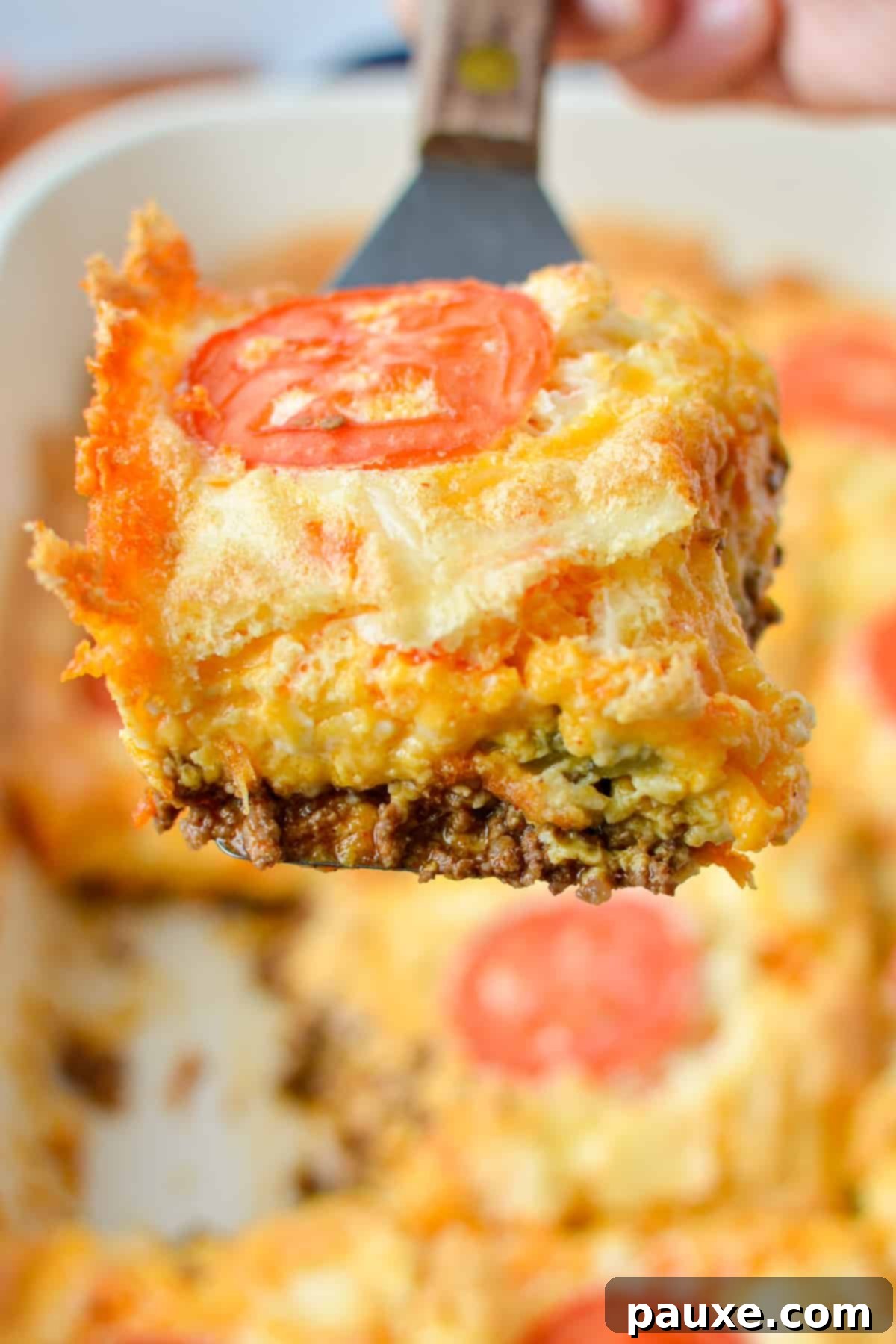 The Duke's Hearty Casserole 2 Lifting a golden slice of cheesy John Wayne taco casserole from a baking dish, showcasing its delicious layers for a hearty meal.