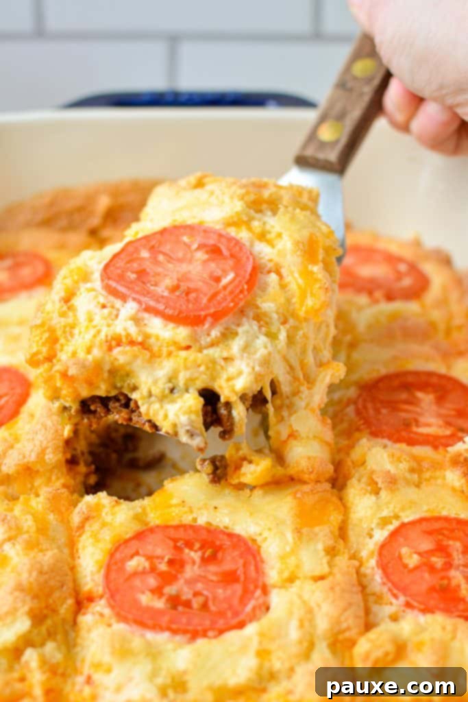 The Duke's Hearty Casserole 10 A serving spoon lifting a generous slice of the cheesy John Wayne Casserole from the baking dish, showing its rich, delicious layers.