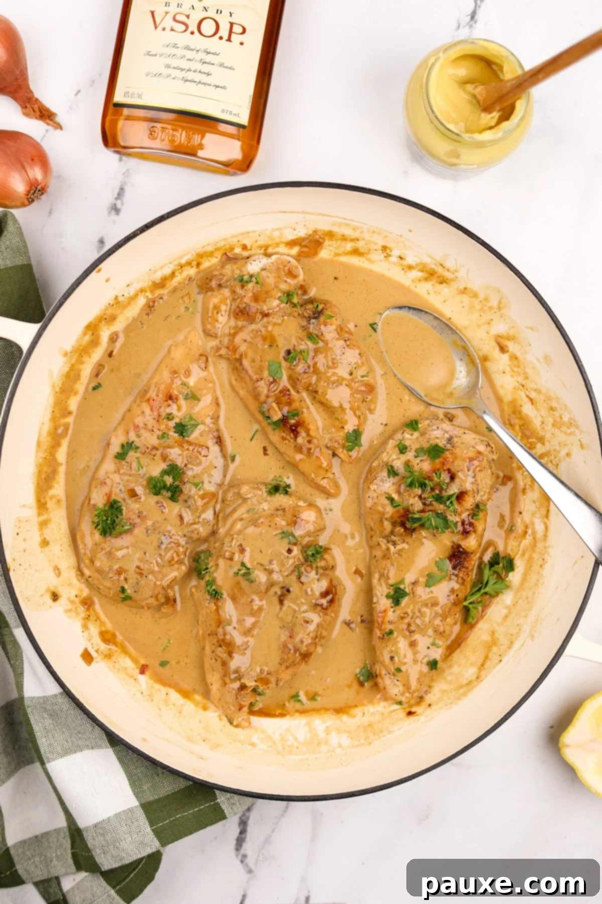 A skillet filled with tender chicken breasts coated in a vibrant, creamy pan sauce, ready to be garnished and served.