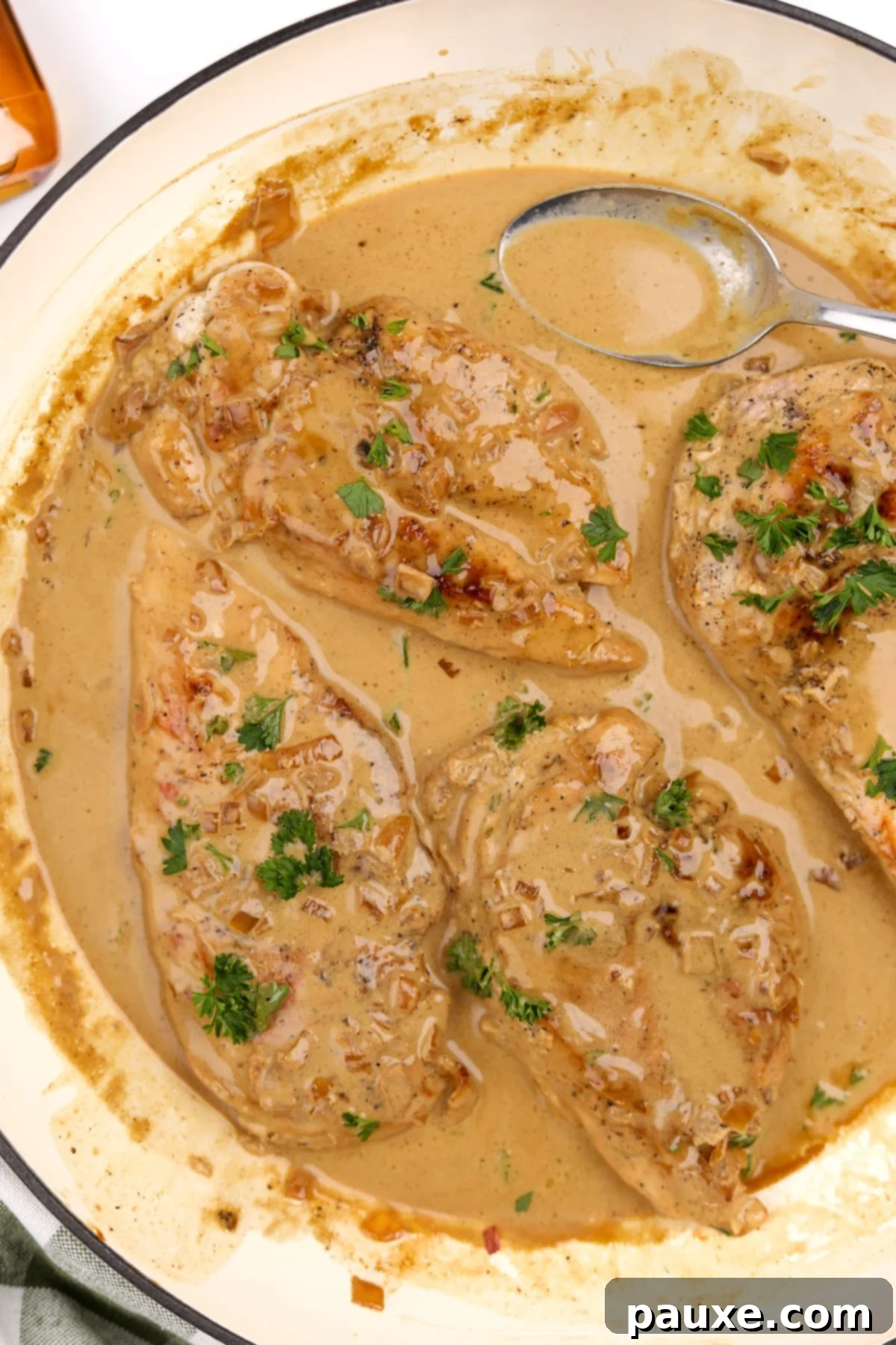 A large skillet filled with perfectly cooked chicken breasts, generously coated in a luxurious, creamy sauce, ready to be served.