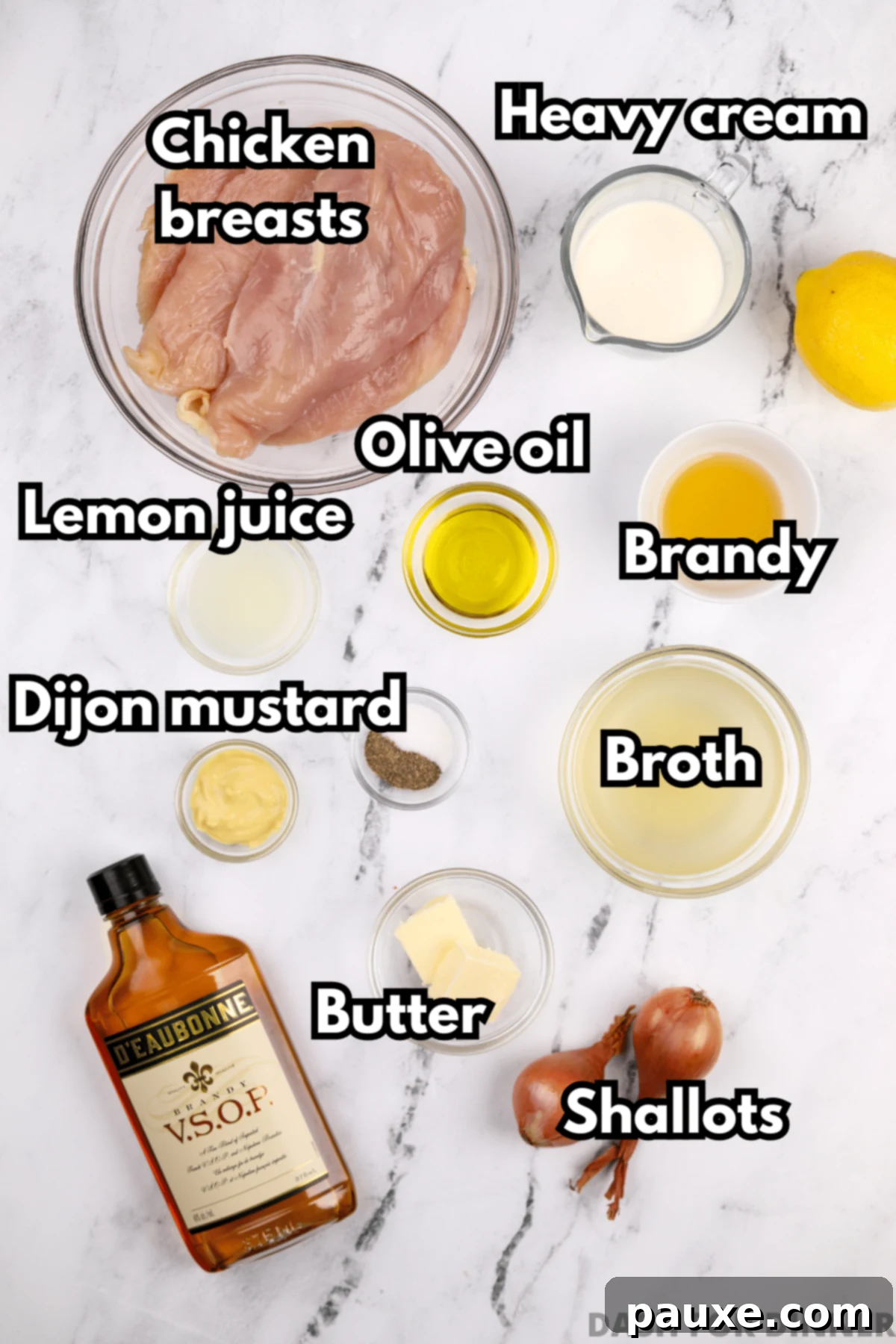 A flat lay photograph of all the essential ingredients for Chicken Diane: chicken breasts, heavy cream, brandy, Dijon mustard, shallot, chicken broth, lemon juice, olive oil, and butter.