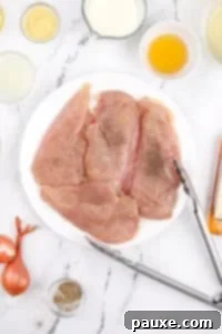 A white plate with chicken cutlets seasoned with salt and pepper.