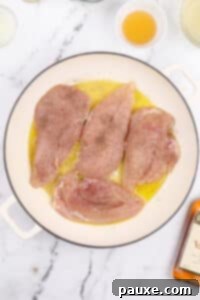 Chicken cutlets added to a skillet with oil and butter.