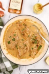 A skillet filled with cooked chicken breasts and a creamy pan sauce.