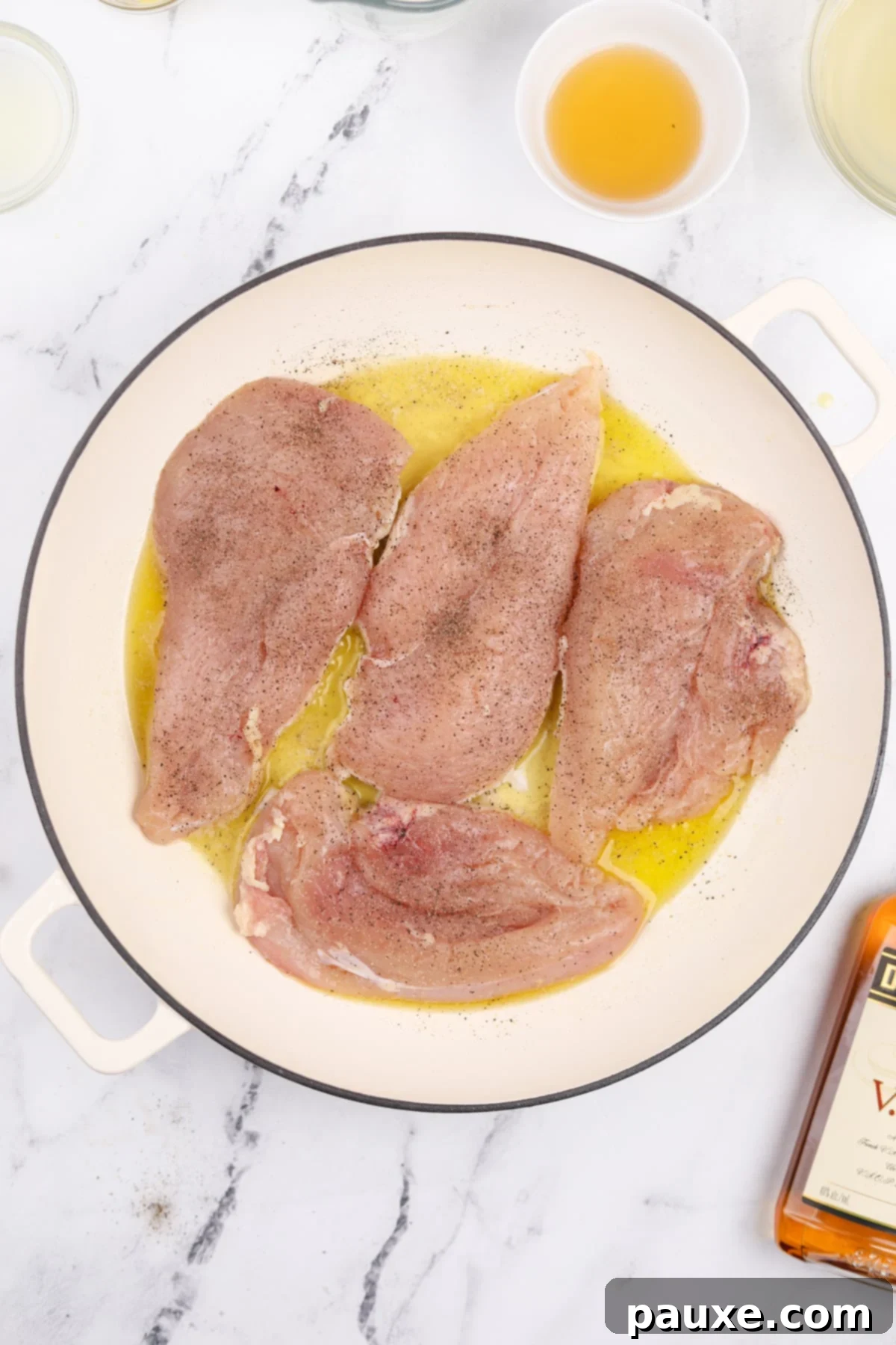 Chicken cutlets being carefully placed into a hot skillet containing melted olive oil and butter.
