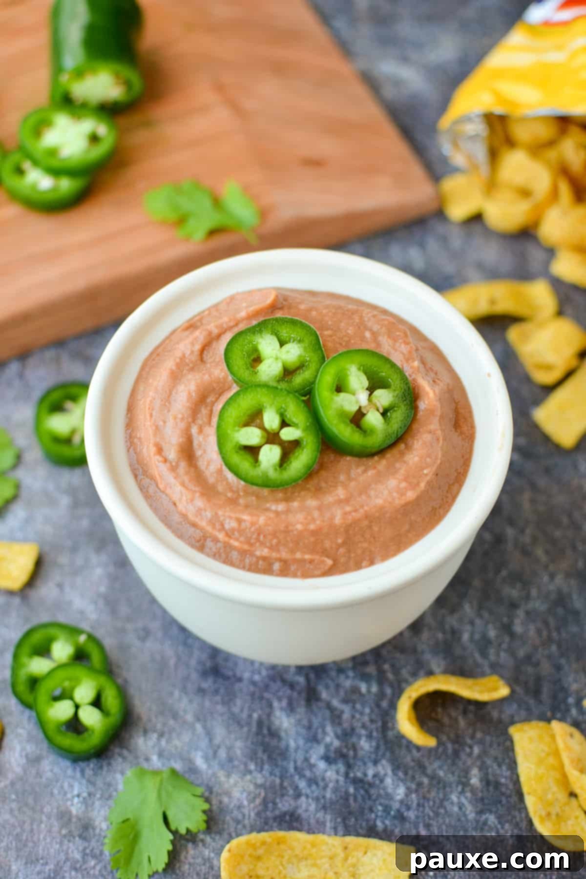 Craveable Homemade Fritos Bean Dip 2 A small bowl of bean dip garnished with jalapeños.